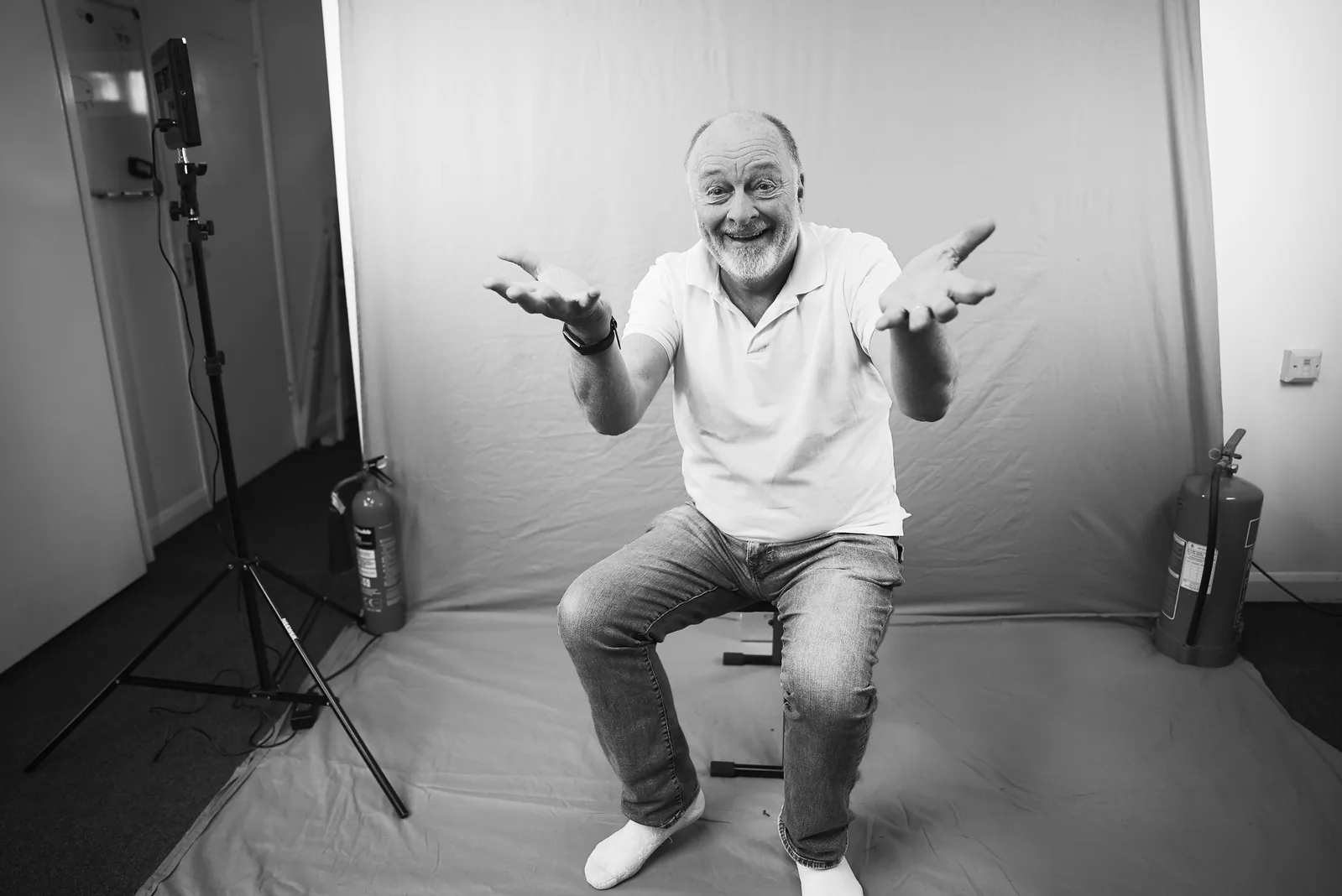 Guy Michelmore in a photo studio, arms spread cheerfully